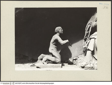 Vorderseite von ICCD [https://www.deutsche-digitale-bibliothek.de/content/lizenzen/rv-ez/] Mittelportal mit Dreiecksgiebel über kompositen DreiviertelsäulenMadonna, flankiert von zwei knienden Gestalten - Linke kniende Figur, rechtes Körperprofil, bh219297_recto. Foto.