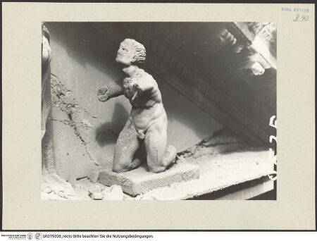 Vorderseite von ICCD [https://www.deutsche-digitale-bibliothek.de/content/lizenzen/rv-ez/] Mittelportal mit Dreiecksgiebel über kompositen DreiviertelsäulenMadonna, flankiert von zwei knienden Gestalten - Rechte kniende Figur, von links, bh219308_recto. Foto.