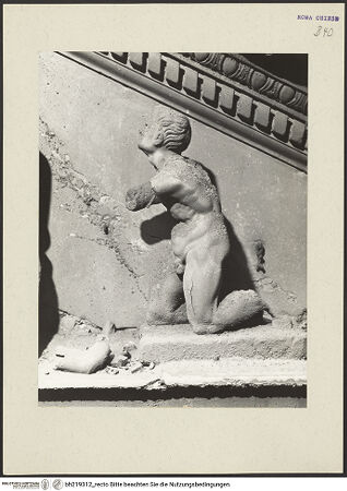 Vorderseite von ICCD [https://www.deutsche-digitale-bibliothek.de/content/lizenzen/rv-ez/] Mittelportal mit Dreiecksgiebel über kompositen DreiviertelsäulenMadonna, flankiert von zwei knienden Gestalten - Rechte kniende Figur, linkes Körperprofil, bh219312_recto. Foto.