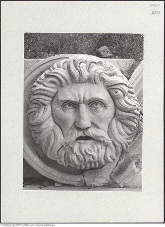 Vorderseite von Sopr. BAS NA [https://www.deutsche-digitale-bibliothek.de/content/lizenzen/rv-ez/] Triumphbogen Alfonsos VGiebelfeld mit zwei Figuren, sogenannte Flussgötter, und Blattgirlande mit zwei Masken - Rahmung, Detail: linke Maske, bh480723_recto. Foto.