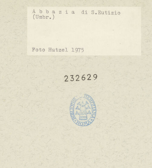 Rückseite von Getty Research Institute [https://www.deutsche-digitale-bibliothek.de/content/lizenzen/rv-ez/] Abbazia di Sant'EutizioSüdwestfassade - Obergeschoss: Fensterrose und Evangelistensymbole, bh232629_recto. Foto: Hutzel, Max.