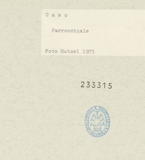 Rückseite von Getty Research Institute [https://www.deutsche-digitale-bibliothek.de/content/lizenzen/rv-ez/] Caso - Ortsansicht mit Glockenturm der Kirche Santa Maria Assunta, bh233315_recto. Foto: Hutzel, Max.